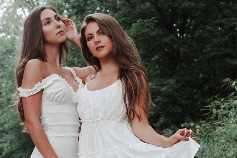 The Wilking sisters in white dresses posing next to a creek.